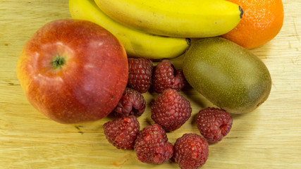 Ein Obsteller mit Himbeeren,Bananen,Mandarinen,Apfel und Kiwi