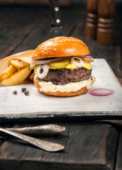 Fresh beef burger with fries on a white wooden board