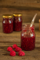 Raspberry jam in a jar on the wooden table