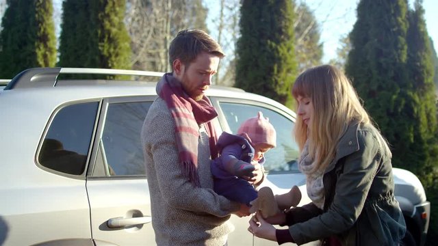 A young mom puts a hat on her baby girl while the dad holds her