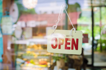 Open sign broad through the glass of door in cafe.