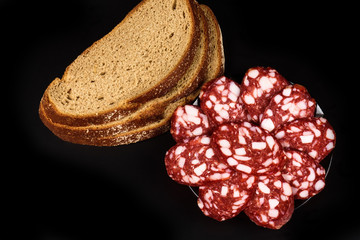 Smoked sausage and bread on a black background