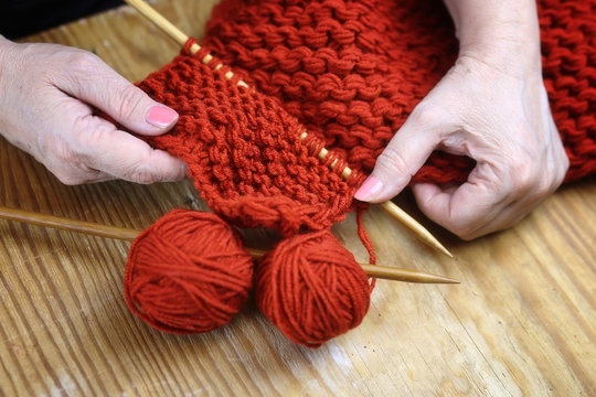 elderly woman is engaged in knitting warm sweaters for her grand
