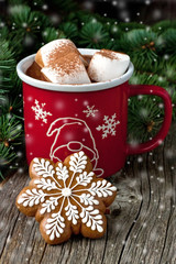 Cup of hot chocolate with marshmallows and gingerbread cookies on a wooden table