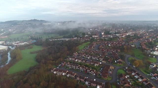 Aerial view of a UK park and housing estate with low clouds.