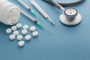 Pills spilling out of pill bottle syringe thermometer and stetho