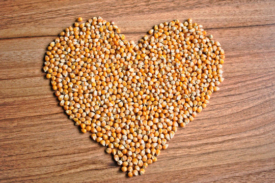 Popcorn kernels in a heart shape on a wooden table