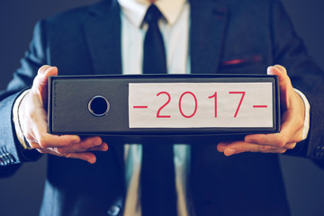 Businessman holding 2017 document ring binder folder