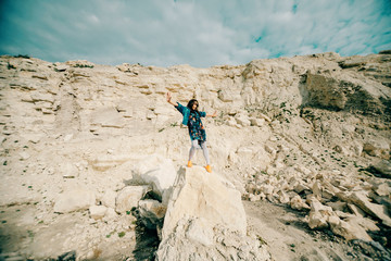 Young woman posing and dancing near the beautiful mountains dressed colorful clothes