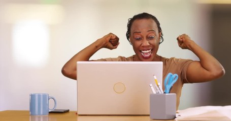 A portrait of an older black woman celebrating while using her computer. An elderly woman laughing and being excited while using her laptop - Powered by Adobe