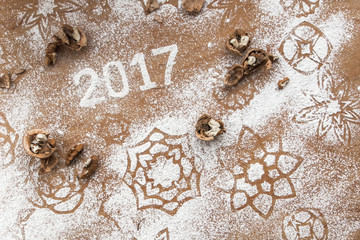 Inscription 2017 written in snow flour on the wooden background, top view. Ingredients for baking biscuit, flour, walnuts