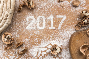 Inscription 2017 written in snow flour on the wooden background, top view. Ingredients for baking biscuit, flour, walnuts
