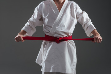 Cropped image of sportsman dressed in kimono tightening red belt