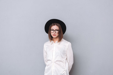 Portrait of a casual girl wearing hat and eyeglasses standing