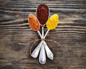 Assortment of spices in vintage spoons on wooden background..