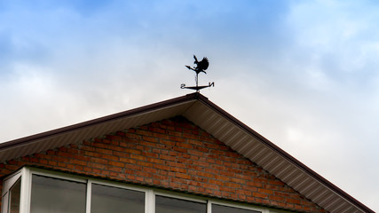 the roof of the house with a weather vane on the roof