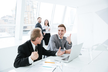 Side view Business partners by table with colleagues on background