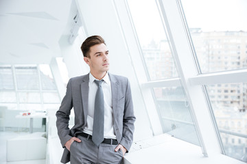 Business man near the window with arms in pockets