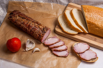 Slices smoked meat or ham on brown packing paper. Tomatoes, garl