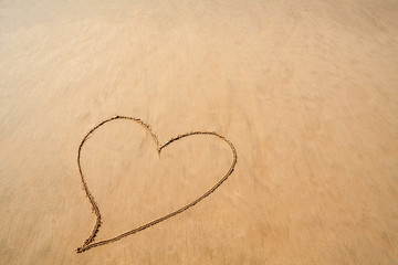 Fototapeta na wymiar Heart drawn in the smooth beach sand for romantic Valentines day celebration