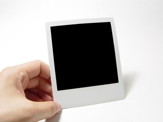 Hand holding up a polaroid frame. Photo memory.
