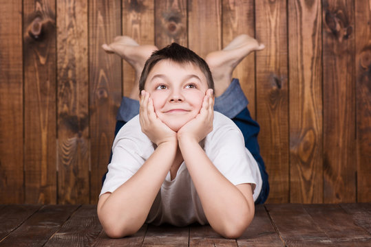Teenager lying on his stomach. Against the background of the wooden planks