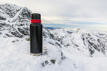 Thermos of tea in the winter in the mountains.