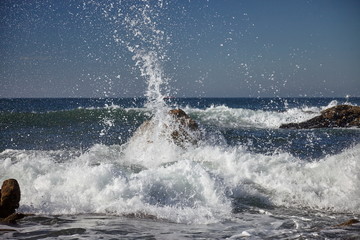 splits waves against rocks in the sea - obrazy, fototapety, plakaty