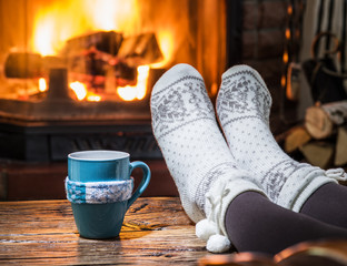 Warming and relaxing near fireplace with a cup of hot drink.