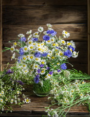 Bouquet of chamomiles and cornflowers in the vase on the wooden