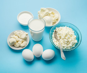Protein products: cheese, cream, milk, eggs on the blue backgrou