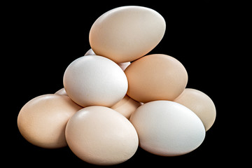 A pile of chicken eggs on black background.