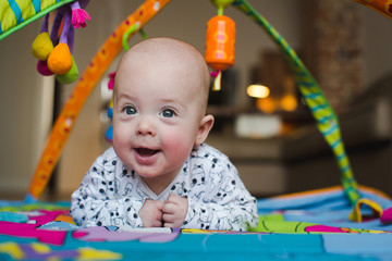 Happy baby boy smiling on playmat close-up