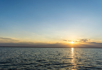 Obraz premium Sunset over sea through light clouds