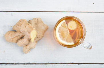 Ginger tea in a glass cup on wooden background