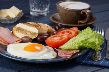 Substantial breakfast with fried egg, salad, bacon, bread and coffee