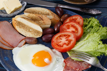 Substantial breakfast with fried egg, salad, bacon, bread and coffee