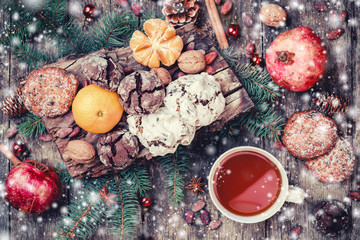 Christmas card. Christmas Cookies Chocolate, tea, pomegranate, Tangerines, Nuts, cocoa beans, Fir branches on wooden snowy background. Christmas and Happy New Year card. Top view, selective focus