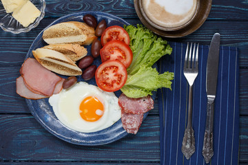 Substantial breakfast with fried egg, salad, bacon, bread and coffee, top view