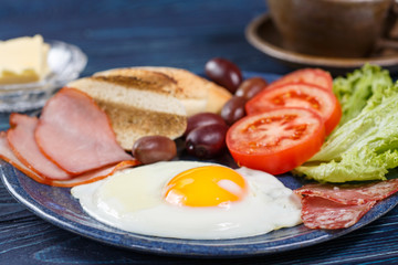 Substantial breakfast with fried egg, salad, bacon, bread and coffee