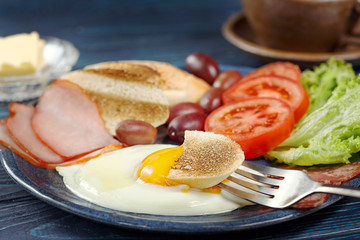 Substantial breakfast with fried egg, salad, bacon, bread and coffee