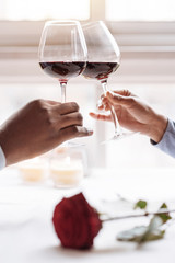 Hands of the African American couple holding wineglasses