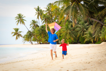 father and little son flying kite on beach