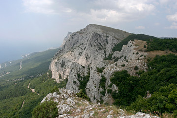 Limestone treed cliffs, the far road and the Black sea coast in Crimean mountains in summer.