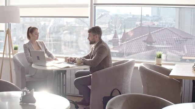Businessman and businesswoman discussing having meeting at coffee break in the cafe and then standing up and shaking hands