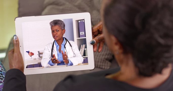 An Older Black Woman Talking To Her African American Doctor Via Video Chat. An Elderly Black Woman Talking To Her Medical Professional On Her Tablet