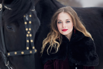 Fototapeta na wymiar beautiful woman with a black horse in winter