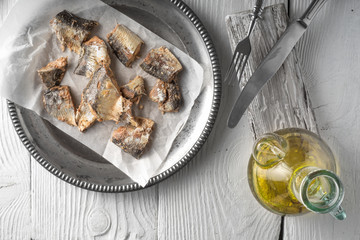 Plate with fish and olive oil on a wooden table