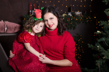 happy family mother and daughter in red dress hugging in the home on Christmas eve. Family look

