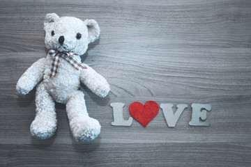 Teddy bear, LOVE letters, heart on wooden background. Place for text. The concept to St. Valentine.